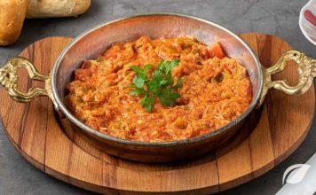 Menemen Tartışmaları Türk Mutfağında Bitmeyen Lezzet Çekişmesi Türk mutfağının en sevilen kahvaltı yemeklerinden biri olan menemen, yıllardır süren büyük bir tartışmanın da merkezinde yer alıyor. Asırlardır sofralarda yer bulan bu lezzet, basit malzemelerle hazırlanmasına rağmen, “Soğansız mı olur yoksa soğanlı mı olmalı?” sorusu etrafında hararetli tartışmalara neden oluyor. Konulu bir haber görseli.
