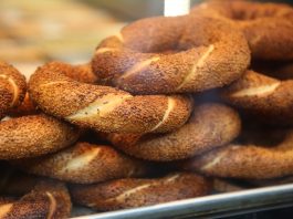 Simit Türk Kültürünün Vazgeçilmez Lezzeti Simit, Osmanlı döneminden günümüze kadar gelen köklü bir geçmişe sahiptir. İlk olarak saray mutfaklarında farklı un karışımlarıyla yapılan bu lezzet, zamanla halk arasında yaygınlaşarak günlük yaşamın bir parçası haline gelmiştir. Özellikle 16. yüzyıldan itibaren İstanbul’da simit fırınlarının açılmasıyla birlikte, bu eşsiz yiyecek şehir kültürünün önemli bir unsuru olmuştur.