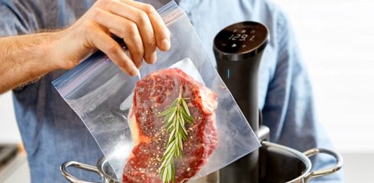 Sous Vide Yöntemiyle Yemeklerde Mükemmel Lezzet Sous vide Fransızca’da “vakum altında” anlamına gelen bir pişirme tekniğidir. Yiyecekler özel poşetlerin içine yerleştirilip vakumlanır ve ardından kontrollü bir şekilde düşük sıcaklıkta su banyosunda pişirilir. Bu yöntem 1970’li yıllarda profesyonel şefler tarafından keşfedilmiş ve zamanla restoran mutfaklarından ev mutfaklarına kadar yayılmıştır. Özellikle et, balık ve sebzelerde istenen pişirme derecesine ulaşmayı kolaylaştırdığı için tercih edilmektedir. Konulu bir haber görseli.