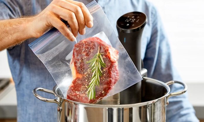 Sous vide Fransızca’da “vakum altında” anlamına gelen bir pişirme tekniğidir. Yiyecekler özel poşetlerin içine yerleştirilip vakumlanır ve ardından kontrollü bir şekilde düşük sıcaklıkta su banyosunda pişirilir. Bu yöntem 1970’li yıllarda profesyonel şefler tarafından keşfedilmiş ve zamanla restoran mutfaklarından ev mutfaklarına kadar yayılmıştır. Özellikle et, balık ve sebzelerde istenen pişirme derecesine ulaşmayı kolaylaştırdığı için tercih edilmektedir. Konulu bir haber görseli.