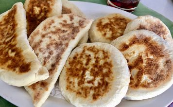 Bazlama: Gelenekten Sofralara Uzanan Sıcak Lezzet Türk mutfağının en özel ve sevilen ekmek çeşitlerinden biri olan bazlama, yumuşak dokusu, doyurucu yapısı ve mis gibi kokusuyla sofraların vazgeçilmezidir. Özellikle Anadolu’nun birçok bölgesinde kahvaltıların, çay saatlerinin ve hatta ana yemeklerin yanında sıklıkla tercih edilen bu ekmek, sadece lezzetiyle değil kültürel bir değer olarak da öne çıkar. Günümüzde modern sofralarda da kendine yer bulan bazlama, hem geleneksel hem de pratik bir lezzet olarak dikkat çekmektedir. Konulu bir haber görseli.