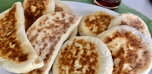 Bazlama: Gelenekten Sofralara Uzanan Sıcak Lezzet Türk mutfağının en özel ve sevilen ekmek çeşitlerinden biri olan bazlama, yumuşak dokusu, doyurucu yapısı ve mis gibi kokusuyla sofraların vazgeçilmezidir. Özellikle Anadolu’nun birçok bölgesinde kahvaltıların, çay saatlerinin ve hatta ana yemeklerin yanında sıklıkla tercih edilen bu ekmek, sadece lezzetiyle değil kültürel bir değer olarak da öne çıkar. Günümüzde modern sofralarda da kendine yer bulan bazlama, hem geleneksel hem de pratik bir lezzet olarak dikkat çekmektedir. Konulu bir haber görseli.
