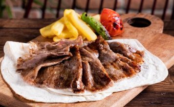 Türk mutfağının en önemli lezzetlerinden biri olan et döner, tarihsel olarak Osmanlı döneminden günümüze kadar uzanan bir yolculuğa sahiptir. Yatay şişlerde pişirilen etlerin zamanla dikey şişlere geçirilmesiyle ortaya çıkan bu yöntem, özellikle hızlı servis imkânı ve eşsiz lezzetiyle kısa sürede halkın gözdesi haline gelmiştir. Dönerin geçmişi, yalnızca bir yemeğin tarihi değil, aynı zamanda Anadolu’nun kültürel çeşitliliğinin de bir yansımasıdır. Konulu bir haber görseli.