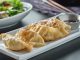 Gyoza: Japon Mutfağının İnce Lezzeti Gyoza, Japon mutfağının en sevilen yemeklerinden biridir ve kökeni Çin’e dayanmaktadır. Aslında Çin’deki jiaozi adı verilen hamur işinden esinlenerek Japonya’ya taşınmış ve zamanla farklı bir kimlik kazanmıştır. Japon mutfağına özgü pişirme teknikleri, gyozayı benzersiz bir hale getirmiştir. Bugün hem Japonya’da hem de dünyanın birçok ülkesinde gyoza, restoranların ve ev sofralarının vazgeçilmez lezzetleri arasında yer almaktadır. Konulu bir haber görseli.