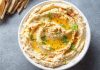 Humus, Orta Doğu mutfağının en bilinen ve sevilen mezelerinden biridir. Başlıca malzemeleri nohut, tahin, limon suyu, sarımsak ve zeytinyağı olan bu özel tarif, yüzyıllardır sofralarda yerini almaktadır. Tarihi çok eski dönemlere dayanan humus, özellikle Lübnan, Suriye, Filistin ve Türkiye gibi bölgelerde yaygın olarak tüketilir. Bugün ise dünya genelinde sağlıklı bir atıştırmalık ya da ana yemek yanında tamamlayıcı olarak tercih edilmektedir. Konulu bir haber görseli.