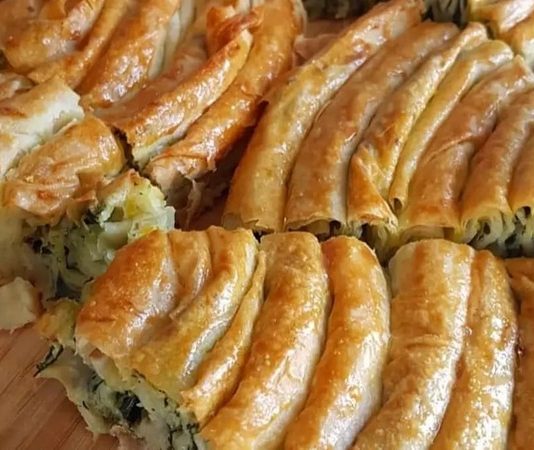 Ispanaklı börek, hem kahvaltı sofralarının hem de özel davetlerin vazgeçilmez lezzetlerinden biridir. İncecik açılmış yufkaların arasında yer alan ıspanak, böreğe hem doğal bir renk hem de zengin bir besin değeri katar. Ispanaklı börek, özellikle ev yapımı olduğunda, hem lezzet hem de sağlık açısından sofralara değer katar. Bu yazımızda ıspanaklı böreğin tarihçesinden malzeme seçimlerine, hazırlık aşamalarından pişirme tekniklerine kadar detaylı bilgiler bulabilirsiniz. Konulu bir haber görseli.