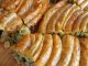 Ispanaklı Börek: Geleneksel Lezzetin Modern Sunumu Ispanaklı börek, hem kahvaltı sofralarının hem de özel davetlerin vazgeçilmez lezzetlerinden biridir. İncecik açılmış yufkaların arasında yer alan ıspanak, böreğe hem doğal bir renk hem de zengin bir besin değeri katar. Ispanaklı börek, özellikle ev yapımı olduğunda, hem lezzet hem de sağlık açısından sofralara değer katar. Bu yazımızda ıspanaklı böreğin tarihçesinden malzeme seçimlerine, hazırlık aşamalarından pişirme tekniklerine kadar detaylı bilgiler bulabilirsiniz. Konulu bir haber görseli.