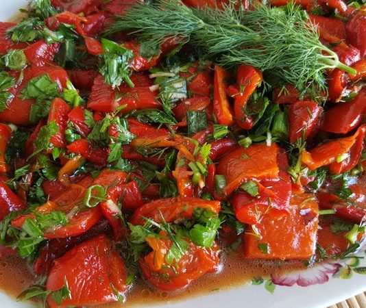 Közlenmiş biber salatası, Türk mutfağının klasik mezelerinden biri olarak bilinir ve sofraların renkli sunumları arasında yer alır. Bu salata, özellikle yaz ve kış sofralarında, hem pratik hem de lezzetli bir başlangıç olarak tercih edilir. Közleme yöntemi, biberlerin aromasını yoğunlaştırır ve salataya karakteristik bir tat katar. Konulu bir haber görseli.