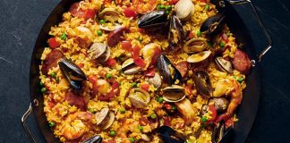 Paella, İspanya’nın en bilinen yemeklerinden biri olarak dünya mutfağında önemli bir yere sahiptir. Özellikle Valencia bölgesinde ortaya çıkan bu yemek, zamanla tüm ülkeye ve oradan da dünyaya yayılmıştır. Tarihi 15. yüzyıla kadar uzanan paella, köylülerin tarlalarda buldukları malzemeleri bir araya getirerek pişirdikleri pratik bir yemek olarak doğmuştur. Konulu bir haber görseli.