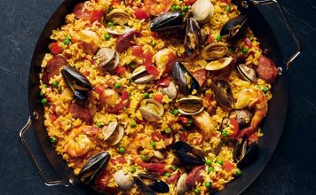 Paella İspanya Mutfağının Renkli Lezzeti Paella, İspanya’nın en bilinen yemeklerinden biri olarak dünya mutfağında önemli bir yere sahiptir. Özellikle Valencia bölgesinde ortaya çıkan bu yemek, zamanla tüm ülkeye ve oradan da dünyaya yayılmıştır. Tarihi 15. yüzyıla kadar uzanan paella, köylülerin tarlalarda buldukları malzemeleri bir araya getirerek pişirdikleri pratik bir yemek olarak doğmuştur. Konulu bir haber görseli.