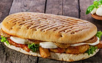 Panini: İtalyan Lezzetinin Hızlı Atıştırması Panini, İtalyan mutfağının en sevilen ve hızlı atıştırmalık seçeneklerinden biridir. Kelime anlamı olarak “küçük ekmekler” anlamına gelen panini, İtalya’da özellikle öğle yemeklerinde tercih edilir. Geleneksel olarak ciabatta veya focaccia ekmeği kullanılarak hazırlanan panini, peynir, et ve sebzelerle zenginleştirilir. Konulu bir haber görseli.