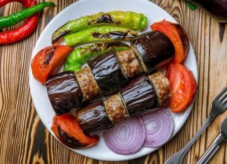 Patlıcan Kebabı: Sofraların Lezzetli ve Geleneksel Yemeği Türk mutfağının vazgeçilmez lezzetlerinden biri olan patlıcan kebabı, özellikle Gaziantep, Şanlıurfa ve Adana gibi şehirlerde sıkça hazırlanır. Patlıcanın közlenip etle buluşmasıyla ortaya çıkan bu yemek, hem hafif hem de doyurucu bir öğün sunar. Osmanlı mutfağından günümüze uzanan tarif, yöresel farklılıklarla her sofrada kendine özgü bir tat bırakır. Konulu bir haber görseli.