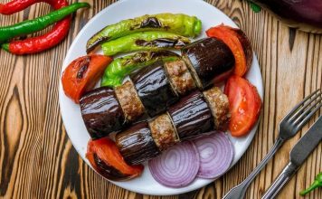 Patlıcan Kebabı: Sofraların Lezzetli ve Geleneksel Yemeği Türk mutfağının vazgeçilmez lezzetlerinden biri olan patlıcan kebabı, özellikle Gaziantep, Şanlıurfa ve Adana gibi şehirlerde sıkça hazırlanır. Patlıcanın közlenip etle buluşmasıyla ortaya çıkan bu yemek, hem hafif hem de doyurucu bir öğün sunar. Osmanlı mutfağından günümüze uzanan tarif, yöresel farklılıklarla her sofrada kendine özgü bir tat bırakır. Konulu bir haber görseli.