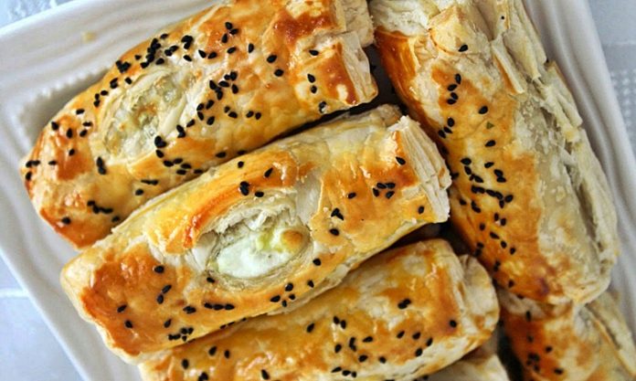 Peynirli börek, Türk mutfağının en özel ve geleneksel lezzetlerinden biridir. Çay saatlerinin en çok aranan eşlikçisi, misafir sofralarının baş tacı ve sabah kahvaltılarının olmazsa olmazı olan bu börek çeşidi, pratik hazırlanışıyla da gönülleri fetheder. Kat kat yufkaların arasına serilen lezzetli peynir harcı sayesinde ortaya çıkan doyurucu tat, hem günlük öğünlerde hem de özel davetlerde sıklıkla tercih edilir. Bugün, peynirli böreğin tarihinden yapılışına, farklı çeşitlerinden püf noktalarına kadar pek çok detayı keşfedeceğiz. Konulu bir haber görseli.