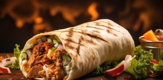 Orta Doğu mutfağının en bilinen sokak lezzetlerinden biri olan Shawarma, ince dilimlenmiş etin özel baharatlarla marine edilip dikey döner üzerinde pişirilmesiyle hazırlanır. Genellikle tavuk, dana veya kuzu eti kullanılır ve lavaş veya pita ekmeğiyle servis edilir. Bu lezzet, hem hızlı hem de doyurucu bir öğün alternatifi sunar. Konulu bir haber görseli.