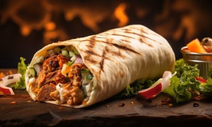 Orta Doğu mutfağının en bilinen sokak lezzetlerinden biri olan Shawarma, ince dilimlenmiş etin özel baharatlarla marine edilip dikey döner üzerinde pişirilmesiyle hazırlanır. Genellikle tavuk, dana veya kuzu eti kullanılır ve lavaş veya pita ekmeğiyle servis edilir. Bu lezzet, hem hızlı hem de doyurucu bir öğün alternatifi sunar. Konulu bir haber görseli.