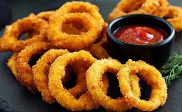 Soğan halkası, fast food kültürünün en sevilen atıştırmalıklarından biri olarak öne çıkıyor. Tarihi 20. yüzyılın ortalarına dayanan bu lezzet, özellikle Amerika’da popülerlik kazanmış ve kısa sürede dünya mutfaklarına yayılmıştır. Patates kızartmaları ve burgerlerin yanında ikincil lezzet olarak sunulan soğan halkaları, hem çıtır dokusu hem de tatlımsı soğan aroması ile dikkat çekiyor. Konulu bir haber görseli.