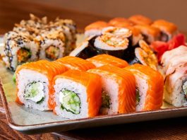 Sushi Roll: Dünyada Popülerliği Artan Japon Lezzeti Sushi roll, Japon mutfağının en bilinen yemeklerinden biridir ve dünya genelinde ün kazanmıştır. İlk olarak Edo döneminde ortaya çıkan sushi, başlangıçta balığın pirinç içinde fermente edilmesiyle hazırlanıyordu. Zaman içinde bu yöntem değişti ve daha modern bir hale geldi. Özellikle 20. yüzyılın ortalarında Amerika’da popülerleşen sushi roll, farklı malzemelerin bir araya gelmesiyle çeşitlenerek bugünkü halini aldı. Konulu bir haber görseli.