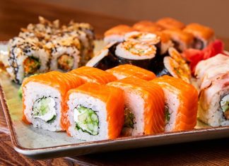 Sushi Roll: Dünyada Popülerliği Artan Japon Lezzeti Sushi roll, Japon mutfağının en bilinen yemeklerinden biridir ve dünya genelinde ün kazanmıştır. İlk olarak Edo döneminde ortaya çıkan sushi, başlangıçta balığın pirinç içinde fermente edilmesiyle hazırlanıyordu. Zaman içinde bu yöntem değişti ve daha modern bir hale geldi. Özellikle 20. yüzyılın ortalarında Amerika’da popülerleşen sushi roll, farklı malzemelerin bir araya gelmesiyle çeşitlenerek bugünkü halini aldı. Konulu bir haber görseli.