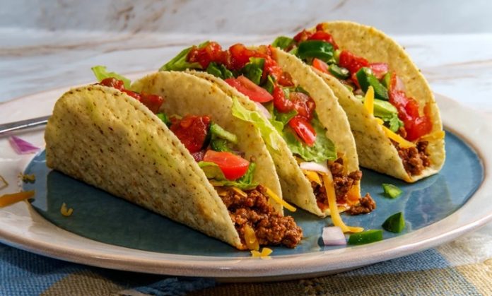 Taco, Meksika mutfağının en bilinen ve sevilen sokak lezzetlerinden biridir. Mısır veya buğday bazlı tortilla içine çeşitli malzemelerin doldurulmasıyla hazırlanır. Tarihi, yüzyıllar öncesine dayanan taco, Meksika halkının günlük beslenmesinde önemli bir yere sahiptir. Konulu bir haber görseli.