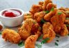 Tavuk nugget, hem çocuklar hem de yetişkinler tarafından çok sevilen bir atıştırmalıktır. Altın rengi çıtır kaplaması ve yumuşak tavuk eti ile mükemmel bir uyum sağlayan nugget, evde veya restoranlarda kolayca hazırlanabilir. Özellikle hızlı atıştırmalık olarak tercih edilen bu lezzet, farklı soslar ile birlikte sunulduğunda sofralara renk katar. Bugün tavuk nugget’in tarihçesinden hazırlama tekniklerine, pişirme yöntemlerinden sunum önerilerine kadar detaylı bir inceleme yapacağız. Konulu bir haber görseli.