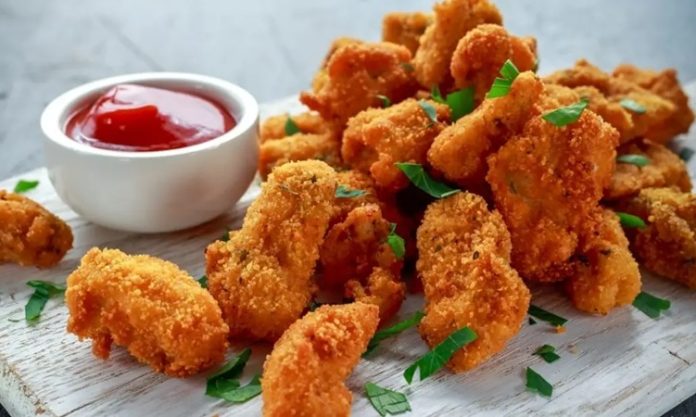 Tavuk nugget, hem çocuklar hem de yetişkinler tarafından çok sevilen bir atıştırmalıktır. Altın rengi çıtır kaplaması ve yumuşak tavuk eti ile mükemmel bir uyum sağlayan nugget, evde veya restoranlarda kolayca hazırlanabilir. Özellikle hızlı atıştırmalık olarak tercih edilen bu lezzet, farklı soslar ile birlikte sunulduğunda sofralara renk katar. Bugün tavuk nugget’in tarihçesinden hazırlama tekniklerine, pişirme yöntemlerinden sunum önerilerine kadar detaylı bir inceleme yapacağız. Konulu bir haber görseli.