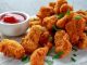 Tavuk Nugget Keyfi: Çıtır ve Lezzetli Atıştırmalık Tavuk nugget, hem çocuklar hem de yetişkinler tarafından çok sevilen bir atıştırmalıktır. Altın rengi çıtır kaplaması ve yumuşak tavuk eti ile mükemmel bir uyum sağlayan nugget, evde veya restoranlarda kolayca hazırlanabilir. Özellikle hızlı atıştırmalık olarak tercih edilen bu lezzet, farklı soslar ile birlikte sunulduğunda sofralara renk katar. Bugün tavuk nugget’in tarihçesinden hazırlama tekniklerine, pişirme yöntemlerinden sunum önerilerine kadar detaylı bir inceleme yapacağız. Konulu bir haber görseli.