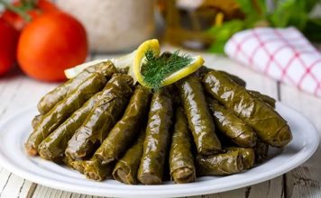 Zeytinyağlı Yaprak Sarma: Sofraların Vazgeçilmez Lezzeti Zeytinyağlı yaprak sarma, Türk mutfağının en sevilen geleneksel lezzetlerinden biridir. Özellikle meze olarak sofralarda sıkça yer alır ve hem hafif hem de besleyici bir alternatif sunar. Yaprak sarması, sadece Türkiye’de değil, Orta Doğu ve Balkan mutfaklarında da farklı yorumlarla hazırlanır. Konulu bir haber görseli.